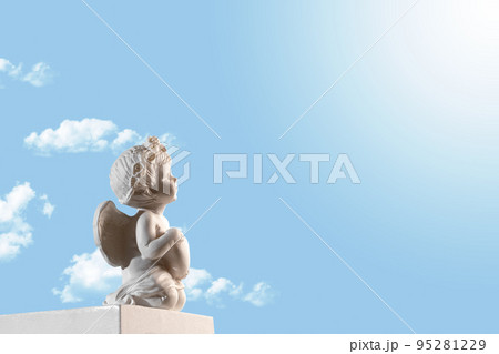 Figurine of an angel Cupid on the podium with a heart on a blu sky with clouds background . Valentine's Day. 95281229