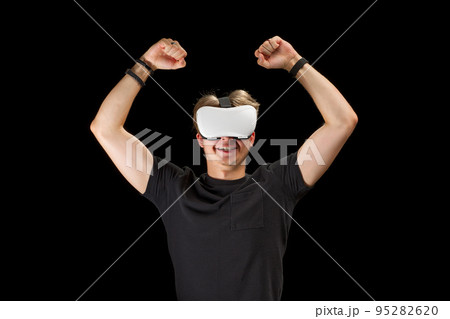 Young man wearing virtual reality VR glasses, goggles isolated on black background. Inside A Metaverse 95282620