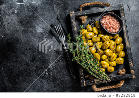 Greek Grilled olives with garlic, olive oil and spices in wooden tray. Black background. Top view. Copy space 95282919