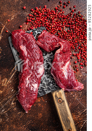 Raw Machete steak and flap steak flank cut on butcher meat cleaver. Dark background. Top view 95282925