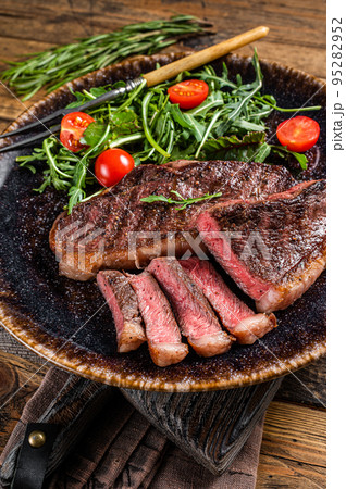 BBQ Grilled cup rump beef meat steak in plate with vegetable salad. Wooden background. Top view 95282952