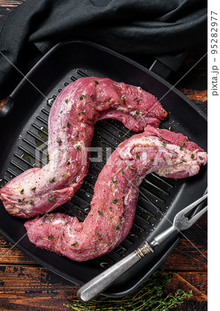 Raw Tenderloin pork fillet ready for cooking, uncooked meat in grill pan with herbs and olive oil. Wooden background. Top view Raw Tenderloin pork fillet ready for cooking, uncooked meat in grill pan with herbs and olive oil. Wooden background. Top view 95282977