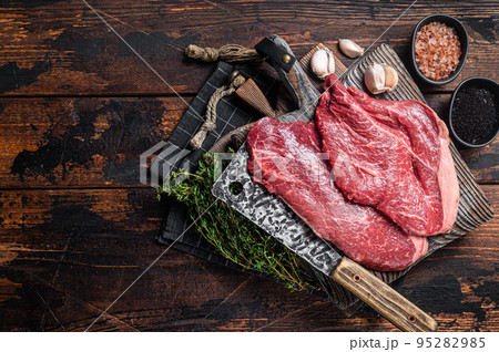 Prime beef veal steaks, raw meat with spices on butcher cutting board. Wooden background. Top view. Copy space Prime beef veal steaks, raw meat with spices on butcher cutting board. Wooden background. Top view. Copy space 95282985