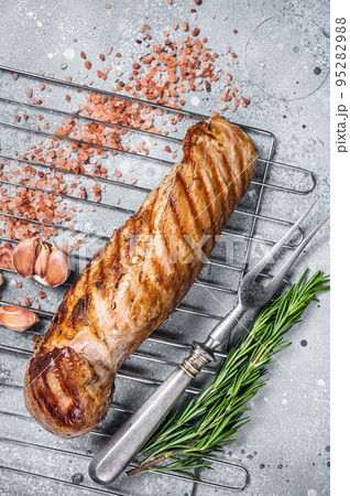 Grilled pork tenderloin fillet meat on grill. Gray background. Top view Grilled pork tenderloin fillet meat on grill. Gray background. Top view 95282988