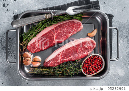 Prime Raw top sirloin beef or cap rump steak in tray with herbs. Gray background. Top view 95282991
