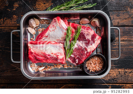 Raw beef Short Ribs in steel tray with rosemary. Wooden background. Top view 95282993