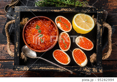 Toasts and Tartlets with Red caviar and butter in wooden tray. Wooden background. Top view 95282994