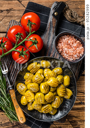 Barbecued organic olives with herbs in plate. Wooden background. Top view Barbecued organic olives with herbs in plate. Wooden background. Top view 95282999
