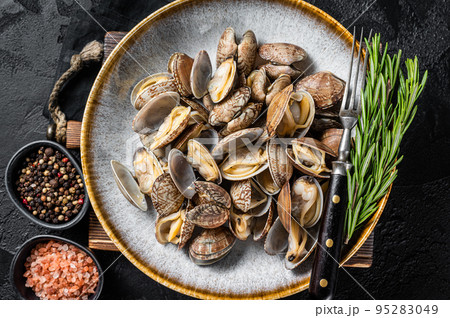 Steamed cooked shells Clams vongole in a plate with herbs. Black background. Top view 95283049