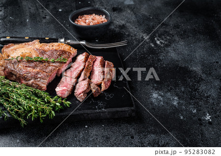 Roasted bbq Chuck Roll beef steaks with herbs. Black background. Top view. Copy space Roasted bbq Chuck Roll beef steaks with herbs. Black background. Top view. Copy space 95283082