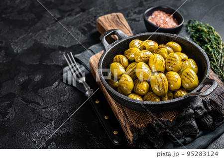 BBQ Grilled olives with garlic, olive oil and spices. Black background. Top view. Copy space 95283124