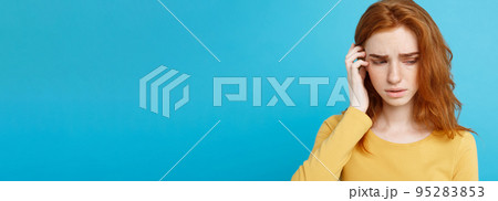 Headshot Portrait of tender redhead teenage girl with serious expression looking at camera. Caucasian woman model with ginger hair posing indoors.Pastel blue background. Copy Space. Headshot Portrait of tender redhead teenage girl with serious expression looking at camera. Caucasian woman model with ginger hair posing indoors.Pastel blue background. Copy Space. 95283853