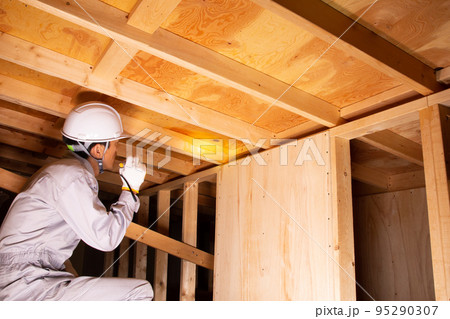 住宅の屋根裏で業務にあたる業者 95290307