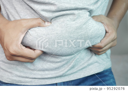 man's hand holding excessive belly fat, overweight concept 95292076