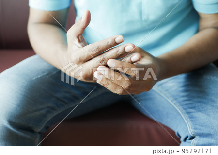 man suffering pain in hand sitting on sofa  95292171