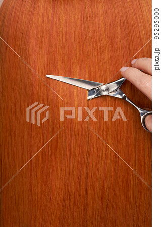 Hairdresser cuts long red hair with scissors Hairdresser cuts long red hair with scissors 95295000