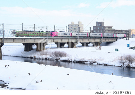 豊平川橋梁上で721系普通列車とすれ違う261系はまなす編成 95297865