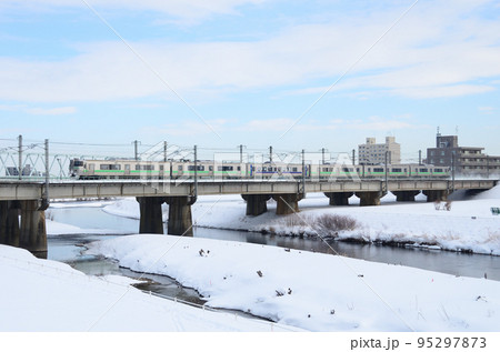 雪煙を上げて豊平川橋梁を札幌駅へ向かう快速「エアポート」 95297873