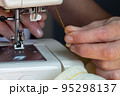 A woman's hand is sewing using an old sewing machine. 95298137