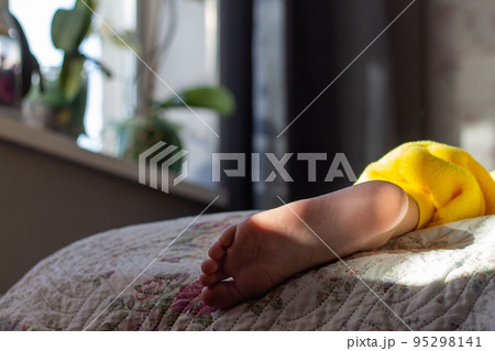 Bare feet in the bed in early morning in the sun 95298141