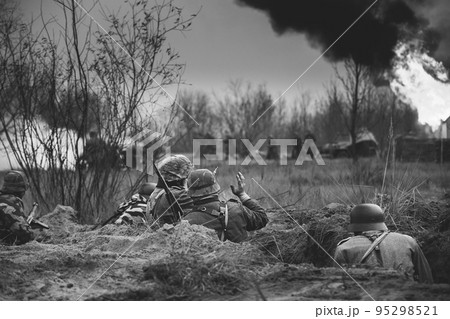 Fight Against Combat Vehicle. Re-enactors Armed Rifles And Dressed As World War Ii German Wehrmacht Infantry Soldiers Fighting Defensively In Trench. Building On Fire On Background. Black White Colors Fight Against Combat Vehicle. Re-enactors Armed Rifles And Dressed As World War Ii German Wehrmacht Infantry Soldiers Fighting Defensively In Trench. Building On Fire On Background. Black White Colors 95298521