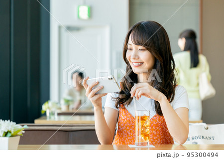 カフェでスマホを見る若い女性 カフェでスマホを見る若い女性 95300494