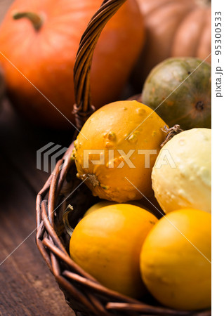 Many small pumpkins in a wicker basket 95300533