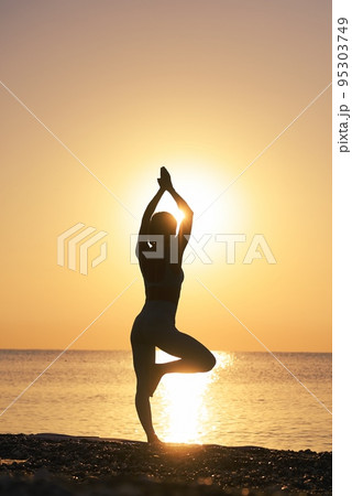 Silhouette young woman practicing yoga on the beach at amazing sunset. Silhouette young woman practicing yoga on the beach at amazing sunset. 95303749
