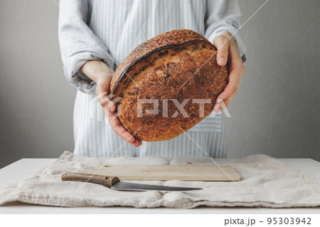 woman baker cooks bread in the kitchen, a cook in a pastry shop holds bread in her hands 95303942