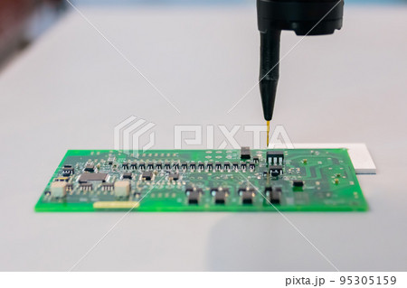 Automatic manipulator with dispenser needle during work with SMT pcb - close up 95305159