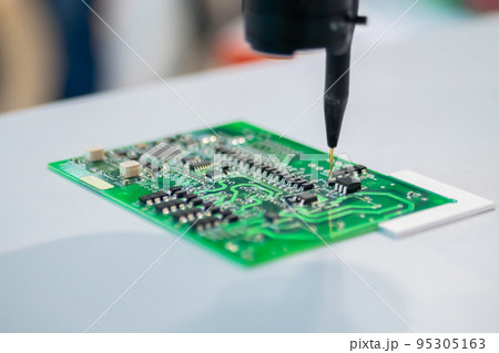 Automatic manipulator with dispenser needle during work with SMT pcb - close up Automatic manipulator with dispenser needle during work with SMT pcb - close up 95305163
