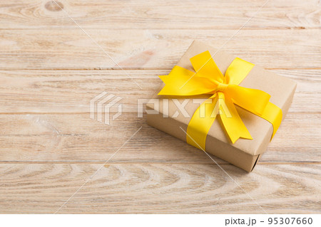 Wrapped christmas or other holiday handmade present in craft paper with colored ribbon. Present box, decoration of gift on table, top view with copy space 95307660