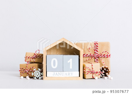 1 january. Christmas composition on colored background with a wooden calendar, with a gift box, toys, bauble copy space 1 january. Christmas composition on colored background with a wooden calendar, with a gift box, toys, bauble copy space 95307677