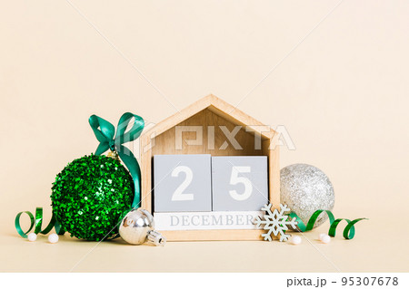 25 december. Christmas composition on colored background with a wooden calendar, with a gift box, toys, bauble copy space 25 december. Christmas composition on colored background with a wooden calendar, with a gift box, toys, bauble copy space 95307678