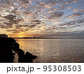 遠くにビルの見える海岸での夕焼け、朝焼け　 95308503
