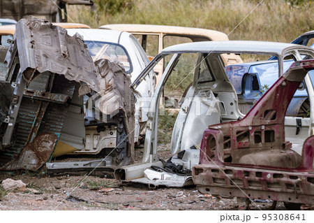 Metal broken car body parts forgotten in junkyard Metal broken car body parts forgotten in junkyard 95308641