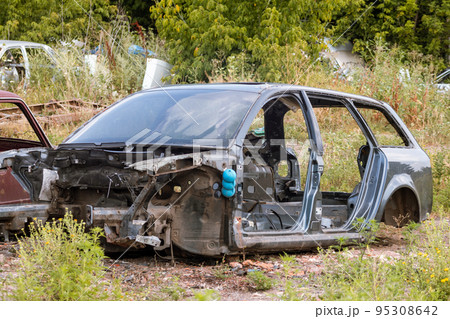 Weathered car body parts abandoned in greenery Weathered car body parts abandoned in greenery 95308642