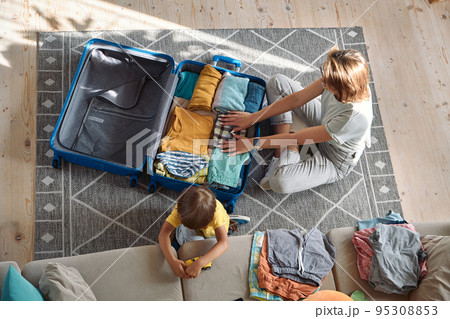 Mother and child are packing things in a suitcase together. Family relocation, flight from the country, closed borders 95308853