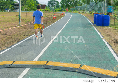 Black and yellow heavy plastic covers for people and vehicle to cross over cables laid on road. Pavement pads to protect electrical wiring on sidewalk in public park. Channel for laying the wires. 95312149