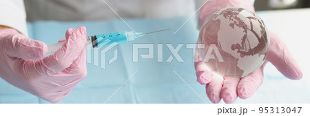 Hands direct a syringe to a glass transparent globe Hands direct a syringe to a glass transparent globe 95313047