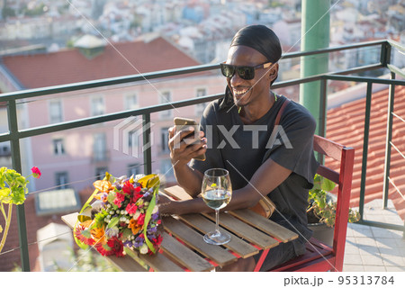Portrait of happy African man waiting for date on roof top 95313784