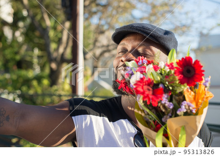 Portrait of happy African American man with bunch of flowers Portrait of happy African American man with bunch of flowers 95313826