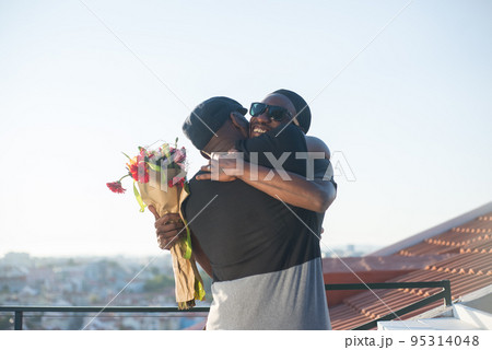 Portrait of African American gay men embracing on roof top 95314048