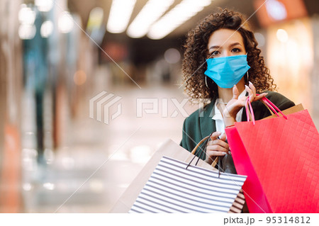 Young woman wearing protection face mask against coronavirus after shopping in the mall. Covid-2019. Young woman wearing protection face mask against coronavirus after shopping in the mall. Covid-2019. 95314812