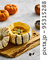 Pumpkin cream soup served in a squash with seeds 95315288