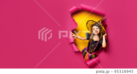 a little girl in a witch costume peeks out of a hole in a paper background a little girl in a witch costume peeks out of a hole in a paper background 95316945