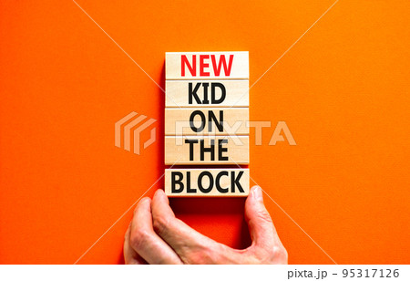New kid on the block symbol. Concept words New kid on the block on wooden blocks. Businessman hand. Beautiful orange table orange background. Business and new kid on the block concept. Copy space. 95317126