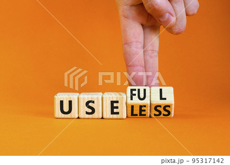 Useful or useless symbol. Concept words Useful or Useless on wooden cubes. Businessman hand. Beautiful orange table orange background. Business useful or useless concept. Copy space. 95317142