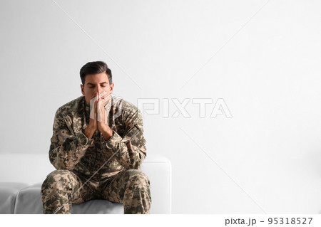 Stressed military officer sitting on sofa against white background. Space for text Stressed military officer sitting on sofa against white background. Space for text 95318527