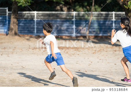 学校の校庭を走っている小学生の男の子と女の子 95318684